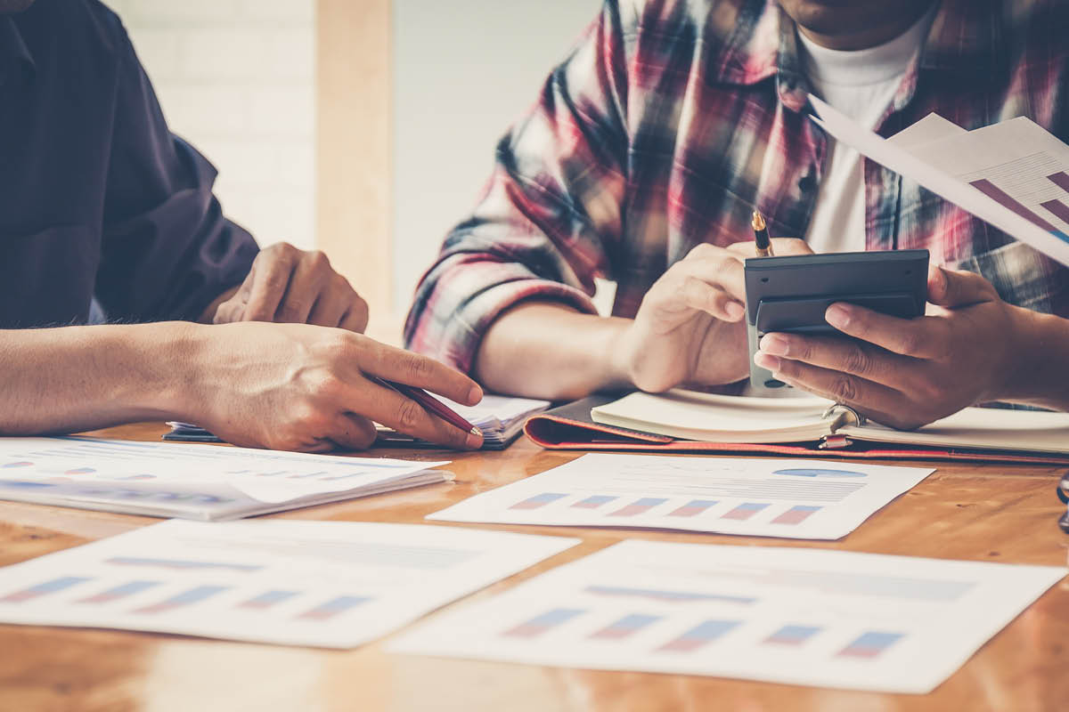 Two people sitting and discussing research and data over a table.