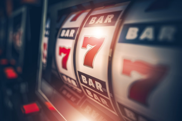 Picture of a gambling slot machine.Picture of a gambling slot machine. The slot machine is showing 3 reels that are all displaying the number 7. Above and below the number 7 you can see the word 'Bar'